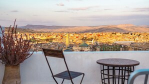 A terrace with a view of a cityscape, including mountains in the distance. - Riad 9 Fez  (Fes)