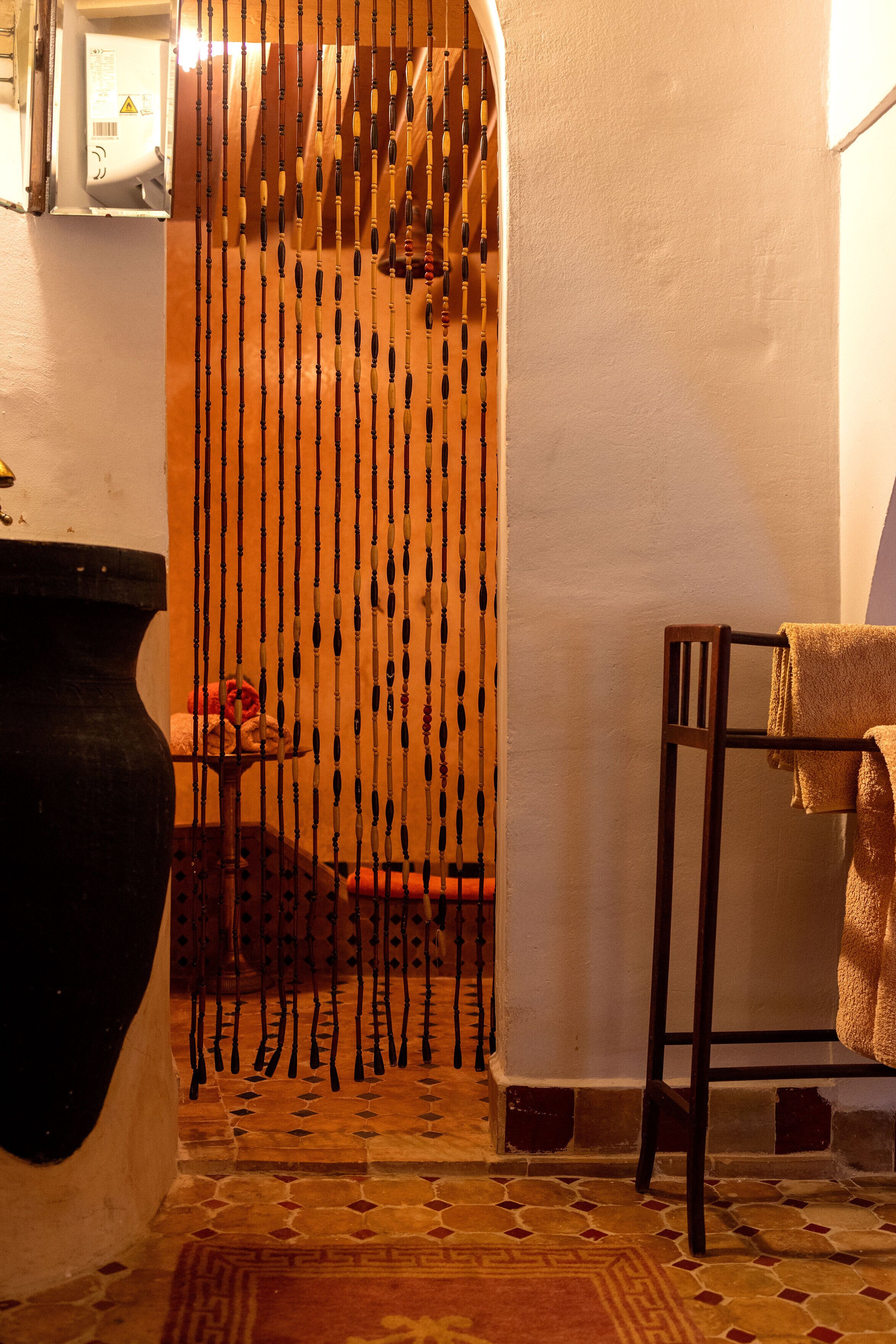 A bathroom with a wooden door, a tiled floor, and a towel rack.