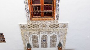 An interior courtyard with a tiled floor, a wooden door, a window with decorative iron bars, and two potted plants. - Riad 9 Fez  (Fes)