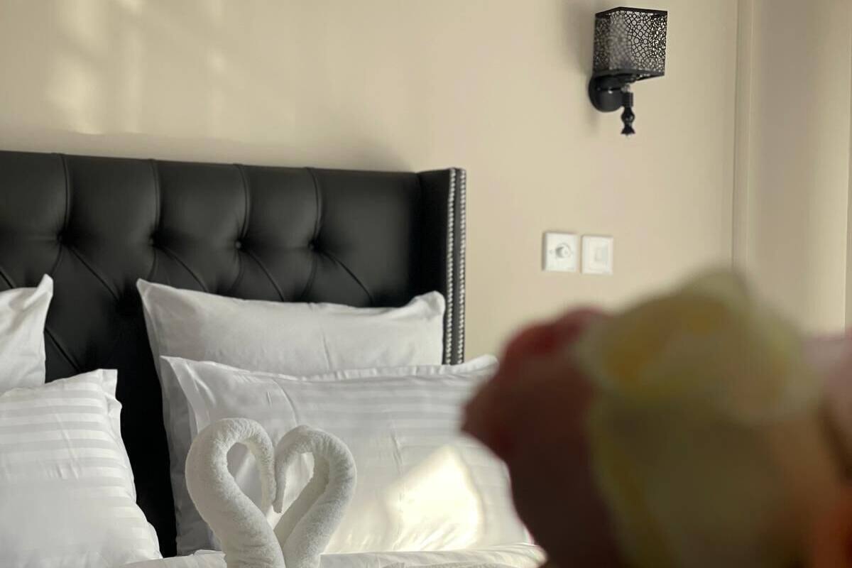 Cama com lençóis brancos e arranjo de travesseiros em forma de cisne.