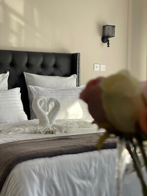 A bed with white linens and a swan-shaped pillow arrangement. - The Ace Hotel (Lusaka)