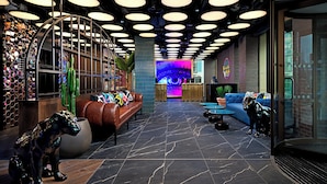 A modern lobby with a central seating area, a digital display, and a unique cactus sculpture. - NYX Hotel Dublin Portobello (Dublin)