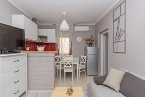 Un espace de vie compact comprenant un coin cuisine, un coin repas et un coin salon.