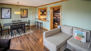 Ein gemütliches Wohnzimmer mit einer Couch, einem Esstisch mit Stühlen und einer Küchenzeile mit Mikrowelle und Kühlschrank.
