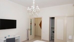 Une chambre à coucher avec un lit, un bureau, une télévision, un lustre et un placard.