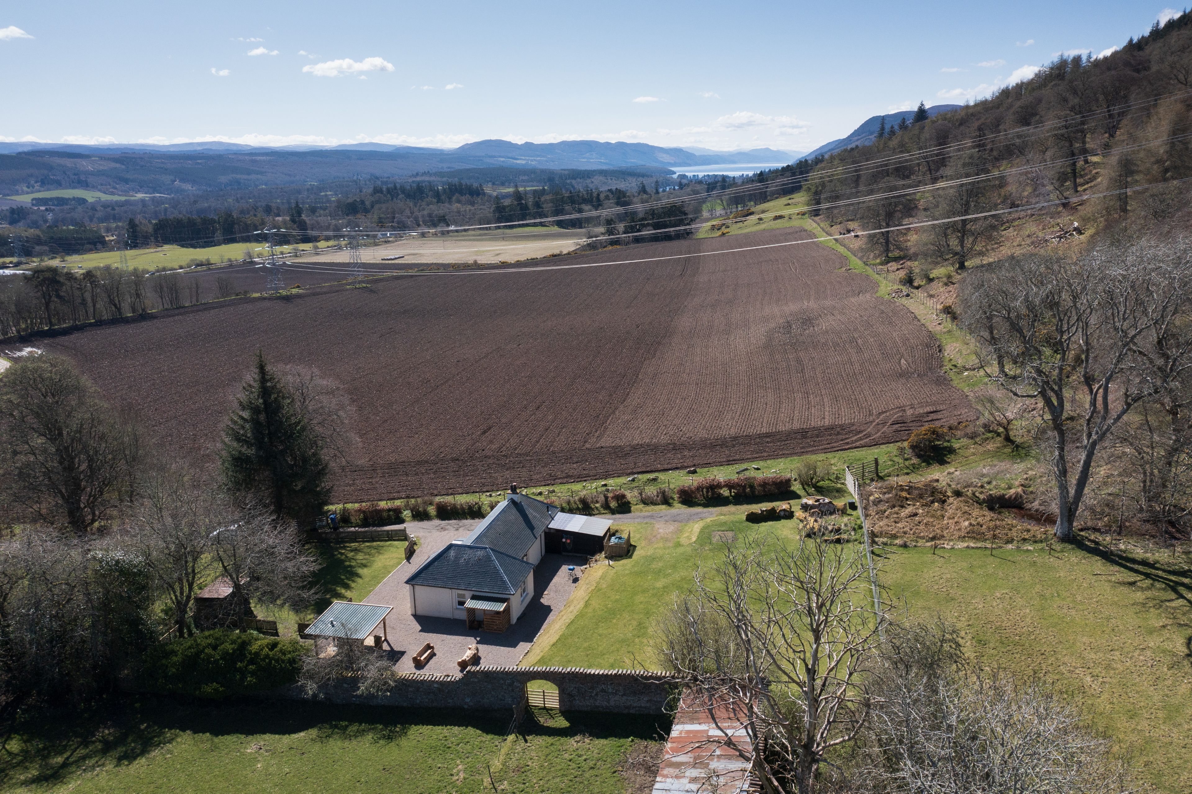 A large, open field with a farmhouse and a solar panel array.