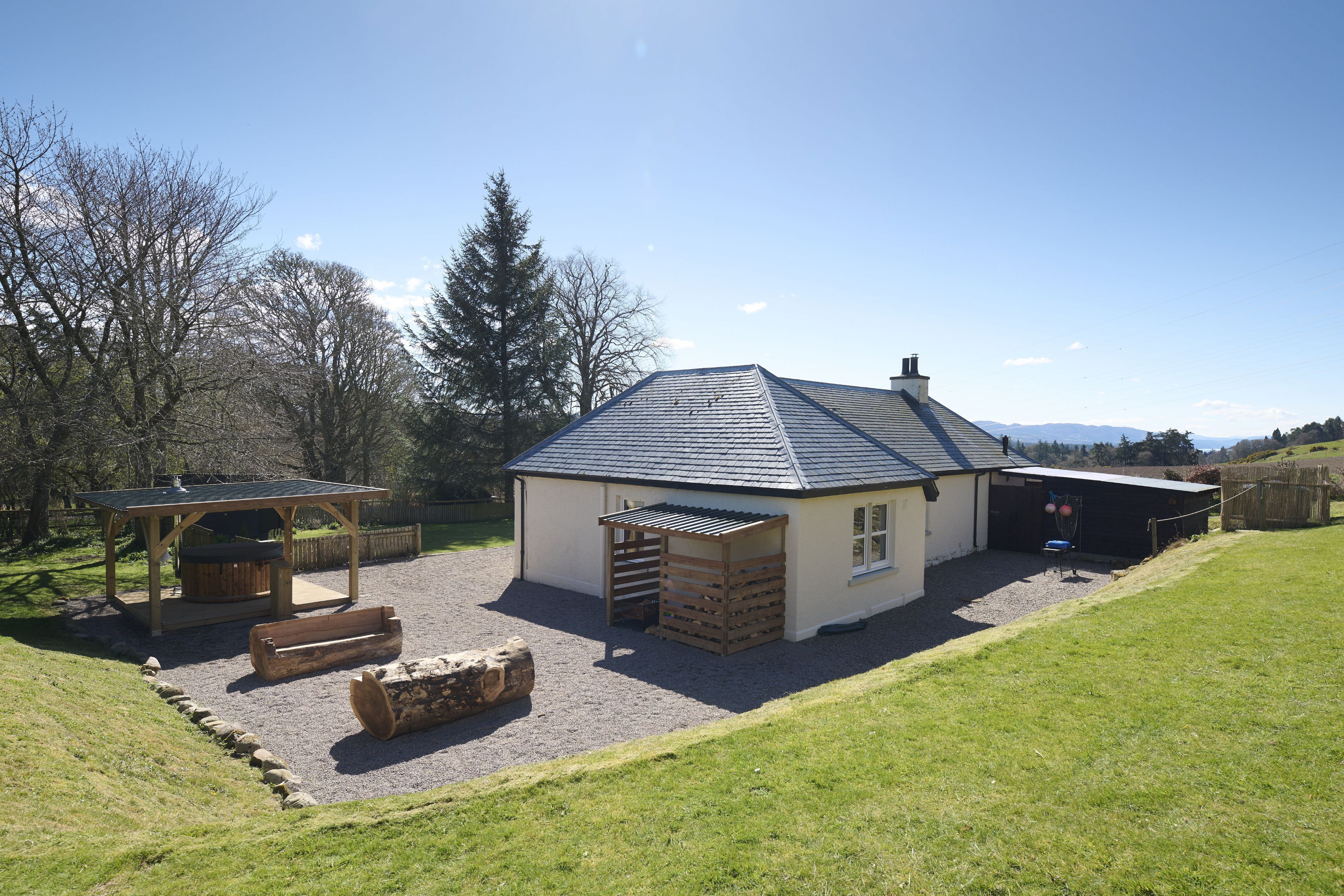 A house with a covered patio, a wooden bench, and a log.
