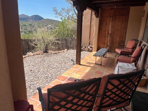 A patio with outdoor seating, a wooden door, and a view of a mountainous landscape.