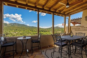 A covered outdoor seating area with a view of a mountainous landscape.