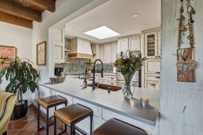 A kitchen with a central island, bar stools, a sink, and a stove.