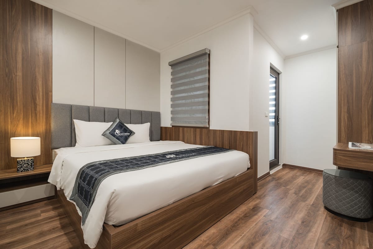 Quarto moderno com estrutura de cama de madeira, cabeceira cinza e mesa de cabeceira com abajur.