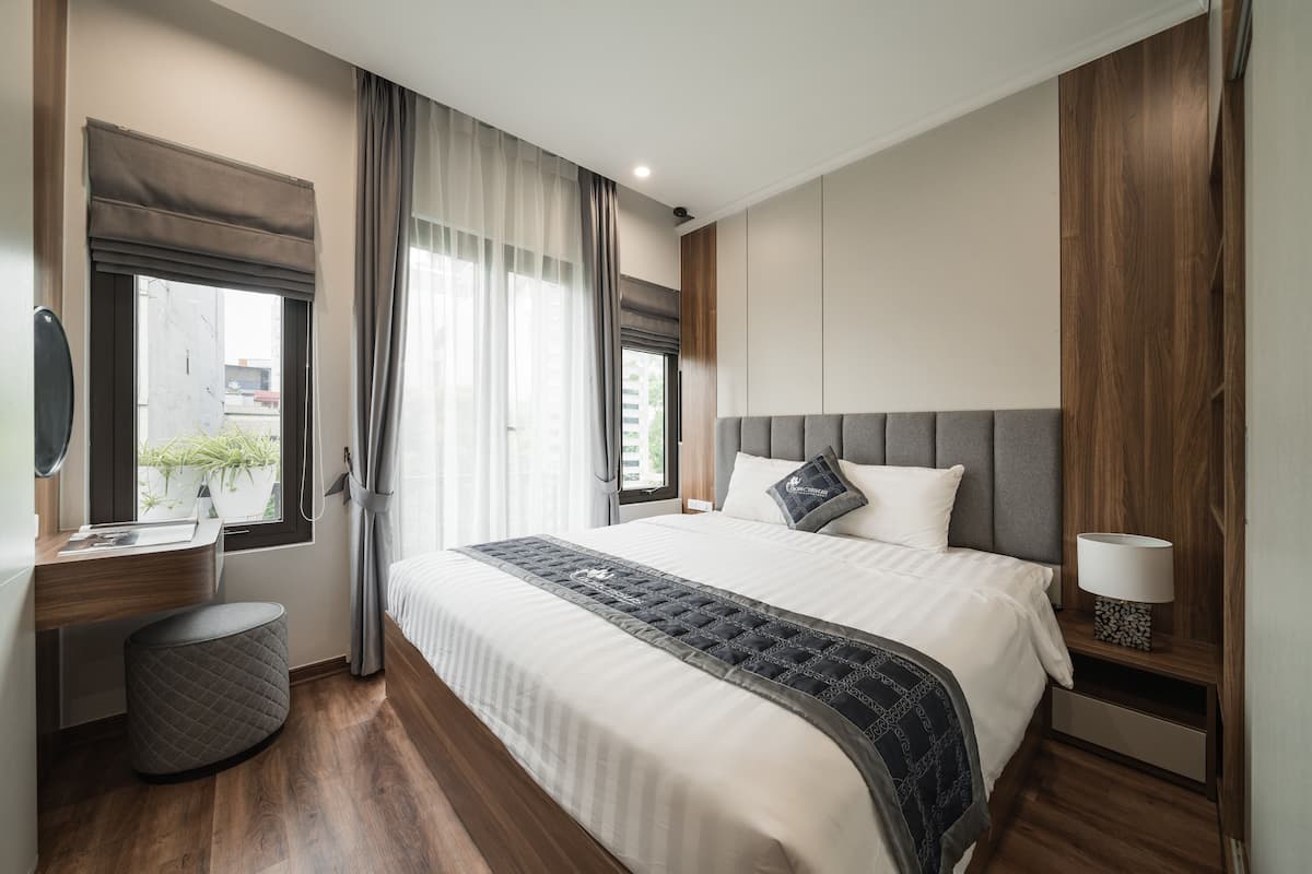 Quarto de hotel moderno com uma cama grande, uma escrivaninha e uma cadeira.
