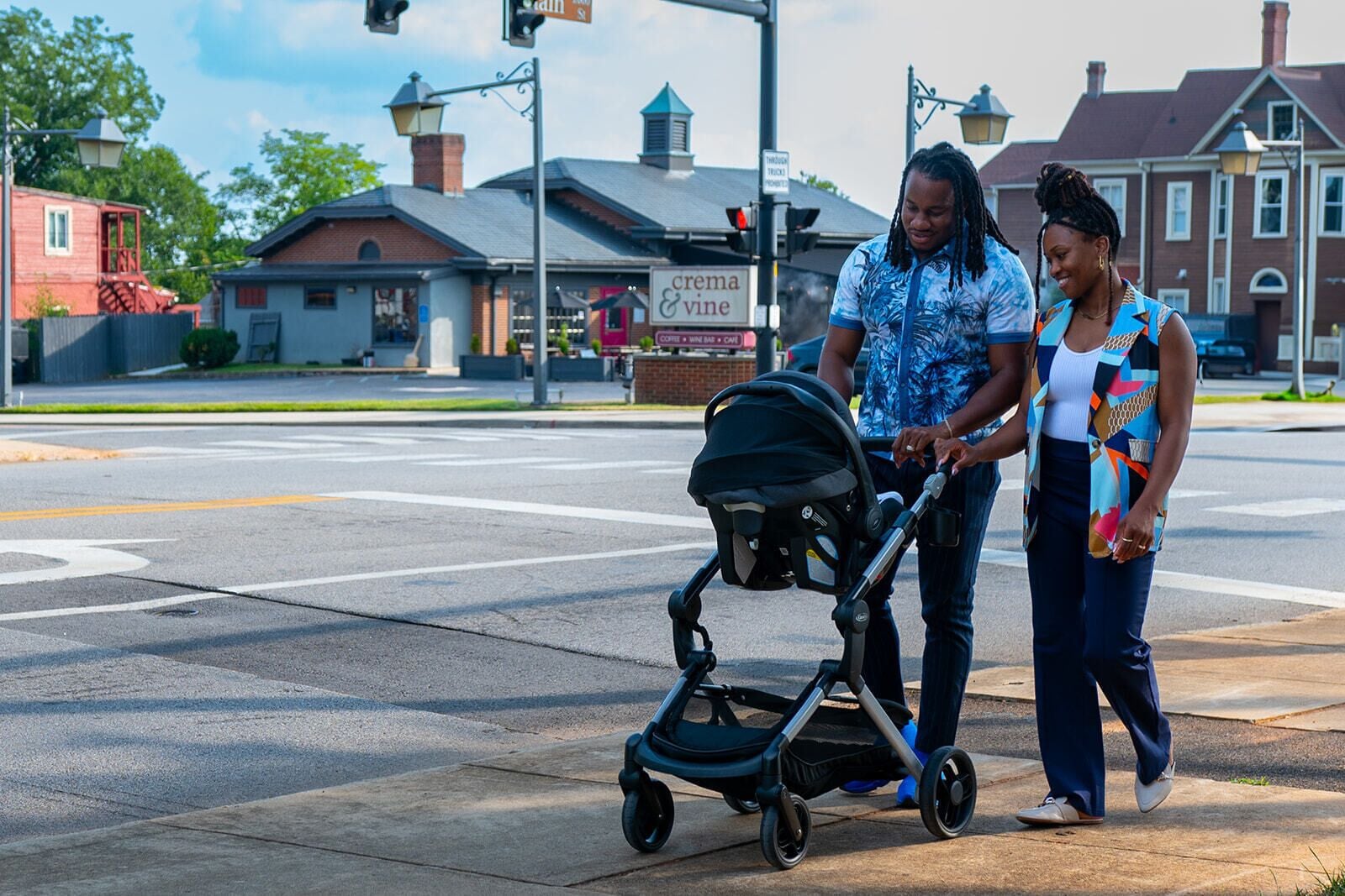 A street scene with a man pushing a stroller and a woman walking beside him.