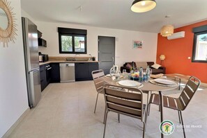 A modern kitchen with a dining area, including a table set for two with plates, glasses, and a pitcher.