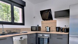Eine moderne Küche mit Geschirrspüler, Backofen, Mikrowelle und Kaffeemaschine.