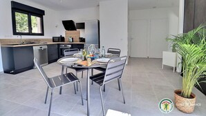 Eine moderne Küche mit Essbereich, ausgestattet mit einem runden Tisch und Stühlen, einem eingebauten Backofen und einem großen Fenster.