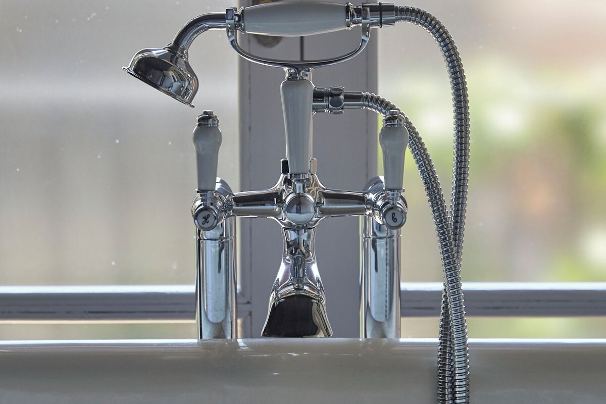 A bathroom with a bathtub, a shower, and a faucet with a hose.