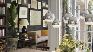 Un salon chaleureux avec un canapé, des étagères, une table basse et des lampes suspendues.