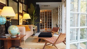 Un salon chaleureux avec un canapé, deux lampes, un globe terrestre et un fauteuil en osier.