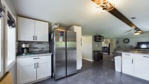 A modern kitchen with white cabinets, a stainless steel refrigerator, and a stone tile floor. - ON THE TRAIL! Newly remodeled, Happy Trails Home (Shingleton)