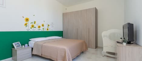 Un dormitorio con cama, armario, televisor y mesita de noche.