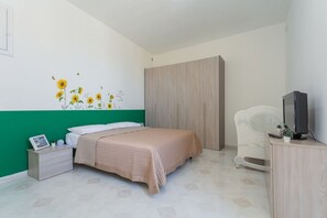 Ein Schlafzimmer mit Bett, Kleiderschrank, Fernseher und Nachttisch.