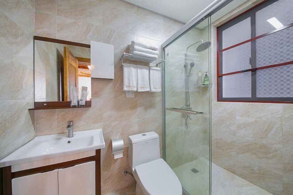 A bathroom with a glass shower enclosure, a sink, a toilet, and a mirror.