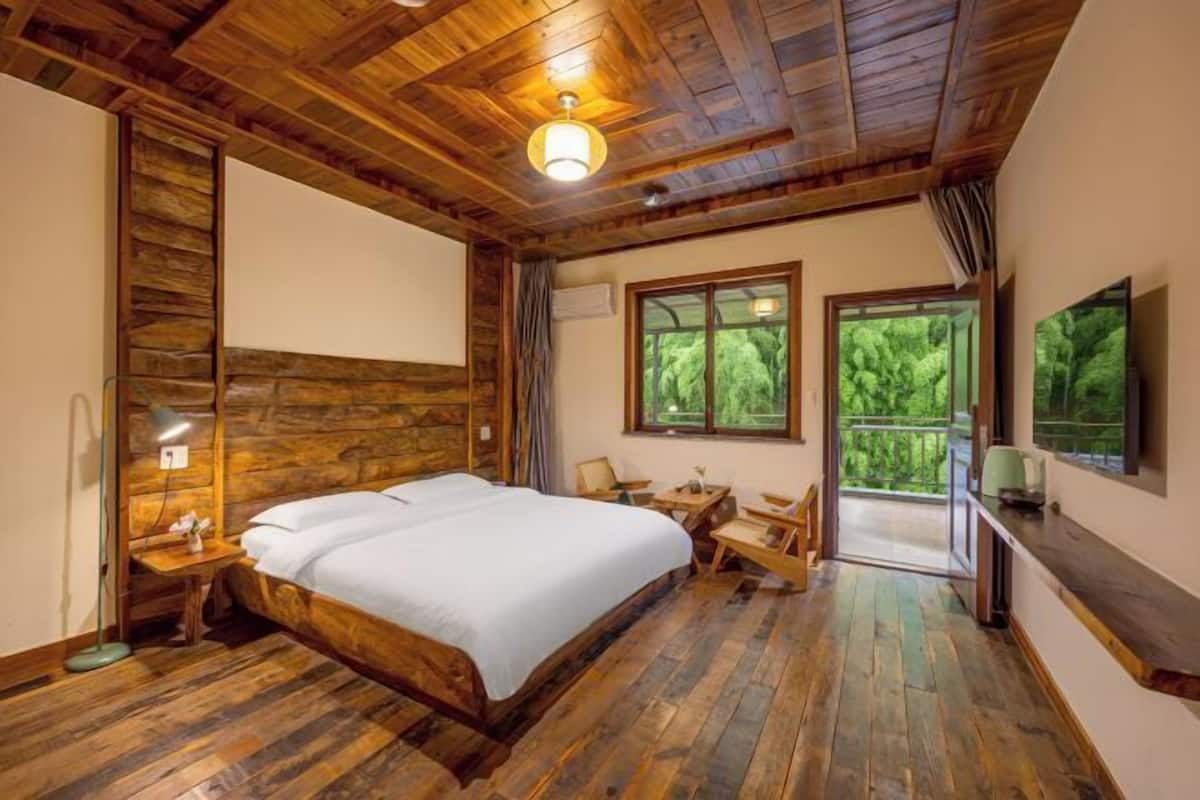 A wooden-paneled bedroom with a bed, a desk, and a chair.