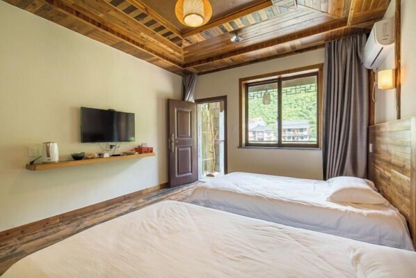 Un dormitorio con dos camas, un televisor en la pared, una ventana con cortinas y techo de madera.