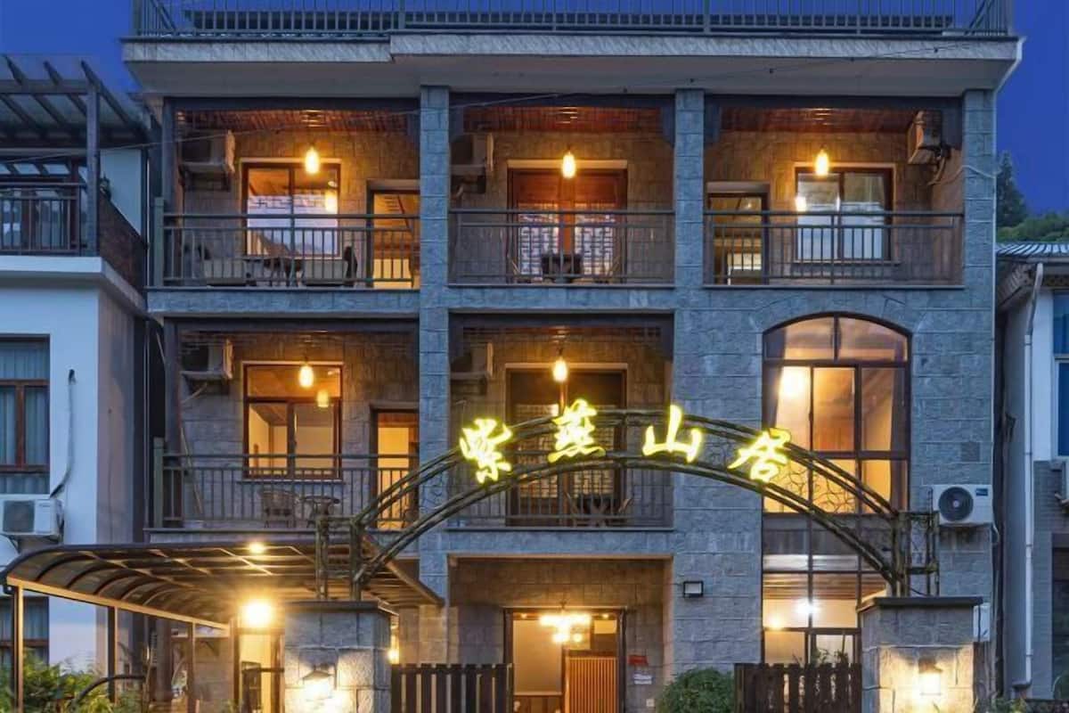 A multi-story building with balconies, a covered entrance, and a neon sign.