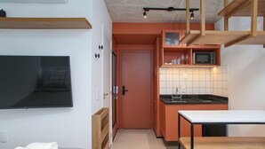 A compact kitchen with a microwave, a sink, and a dining area with a table and chairs. - VN Frei Caneca (São Paulo)