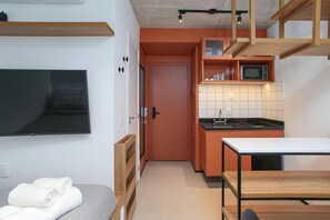 Una cocina compacta con microondas, un lavamanos y un comedor con mesa y sillas.