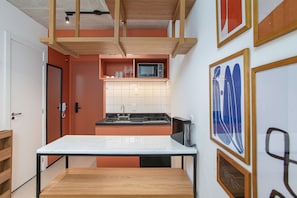 A compact kitchen with a microwave, sink, and wooden cabinets. - VN Frei Caneca (São Paulo)