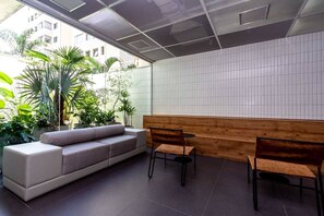Un interior moderno con un sofá, dos sillones, un banco de madera y una pared de azulejos.
