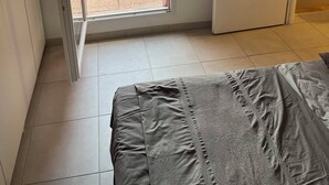 Et soveværelse med en seng, en skydedør til en udendørs terrasse med en stol og et bord.