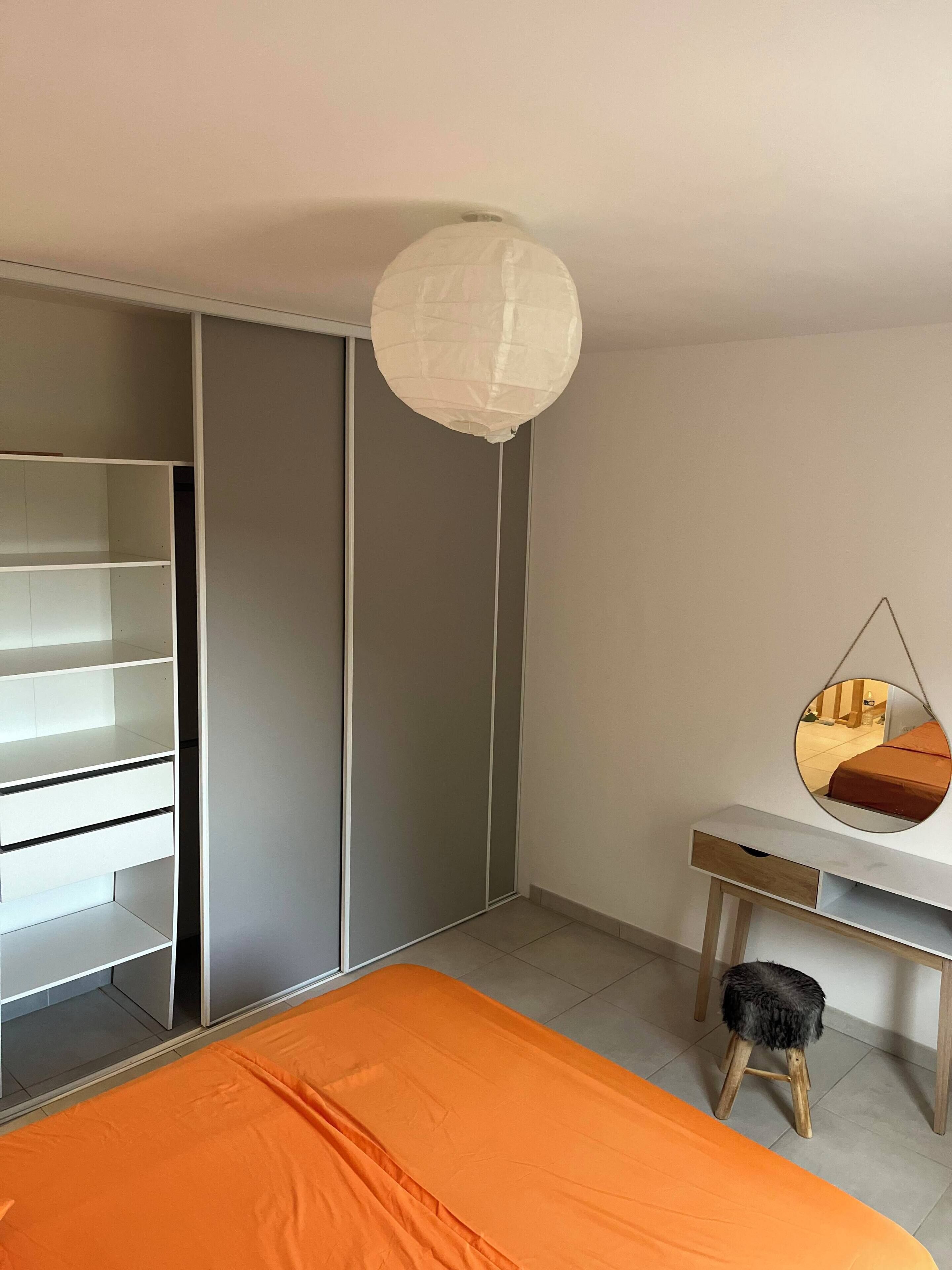 A bedroom with a bed, a wardrobe, a desk, and a hanging chair.