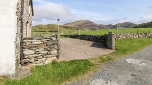 A rural landscape with a stone wall, a building, and a fenced field. - Ereiniog (Garndolbenmaen)