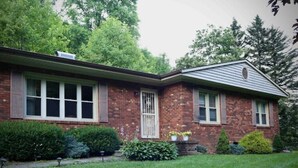 A two-story brick house with a front porch, a small garden, and a garage. - Creekside Rural Retreat in Beautiful Ashe County
 (Lansing)