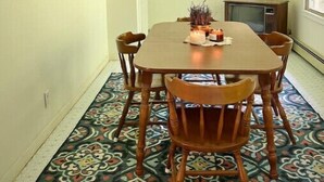 A dining area with a wooden table, six chairs, a chandelier, and a television on a stand. - Creekside Rural Retreat in Beautiful Ashe County
 (Lansing)
