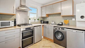 A modern kitchen with stainless steel appliances, wooden cabinets, and a window providing natural light. - Cosy Apartment 5 guests - 3 beds + 1 sofa bed Lewisham, London (London)