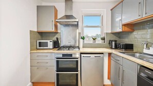 A modern kitchen with stainless steel appliances, a microwave, a gas stove, a dishwasher, and a sink. - Cosy Apartment 5 guests - 3 beds + 1 sofa bed Lewisham, London (London)