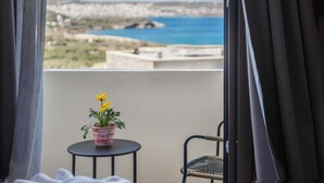 A balcony with a potted plant, a chair, and a view of the sea and rocky landscape. - Casa di Demezzo (Sitia)