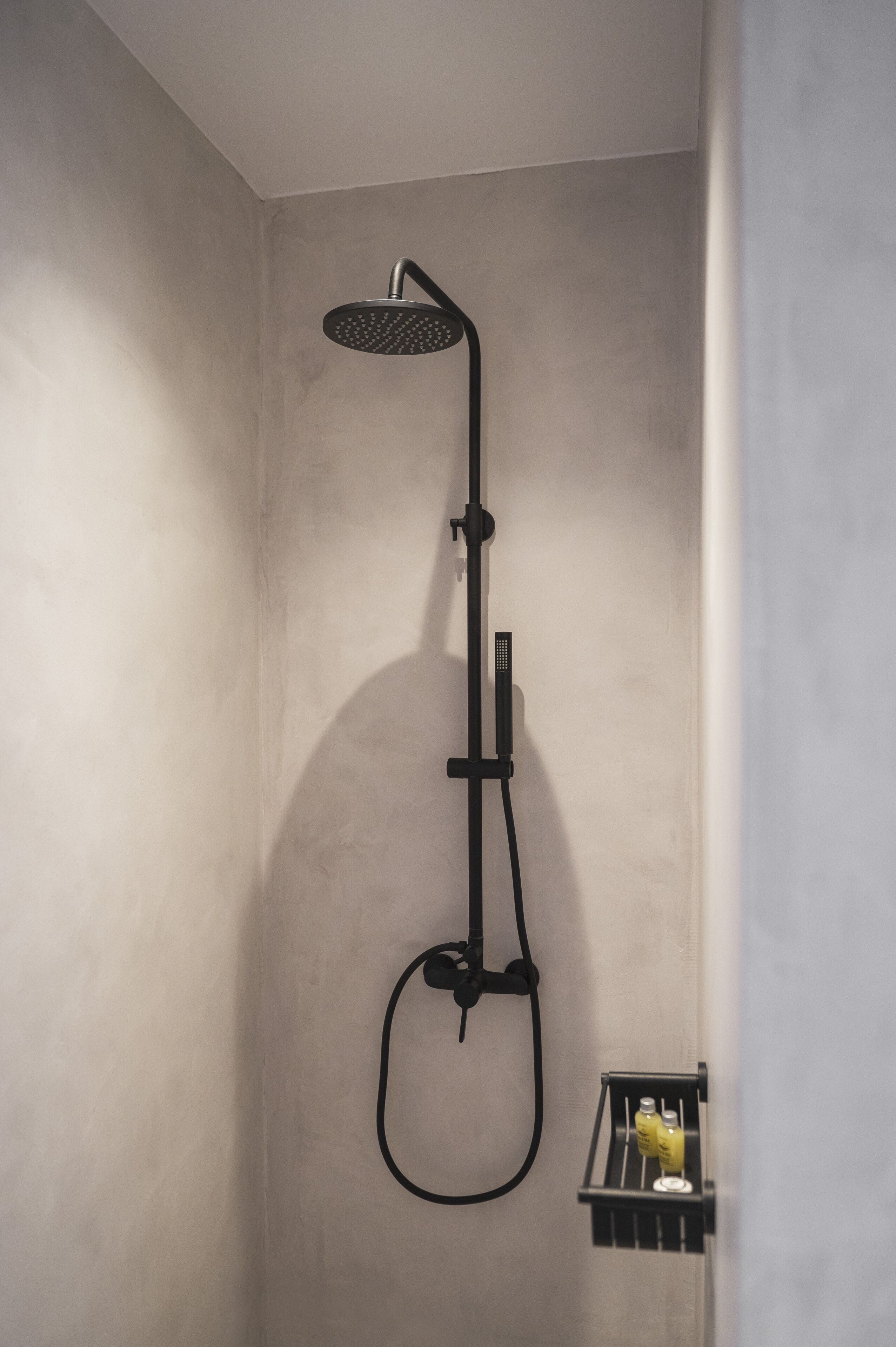 A modern shower with a handheld showerhead and a wall-mounted control panel.