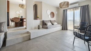 A modern living room with a sofa, a dining table, and chairs. There is a staircase leading to another room. - Casa di Demezzo (Sitia)