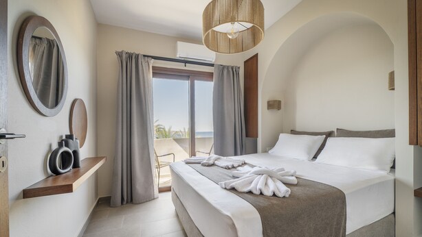 A hotel room with a bed, a large mirror, a wooden shelf, and a view of the outdoors. - Casa di Demezzo (Sitia)