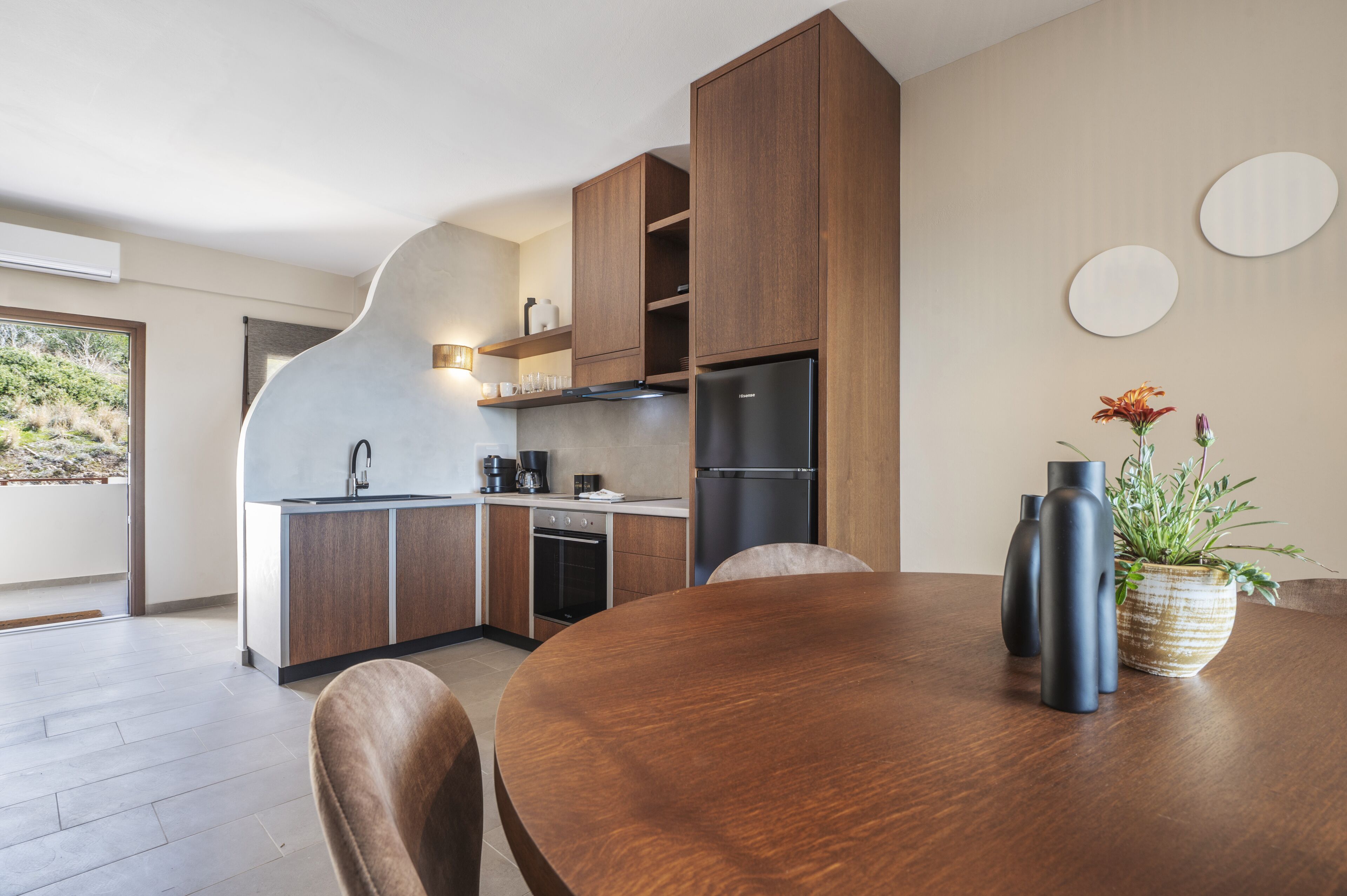 A modern kitchen with wooden cabinets, a black refrigerator, and a dining table with chairs.