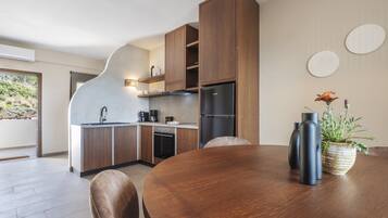 A modern kitchen with wooden cabinets, a black refrigerator, and a dining table with chairs.