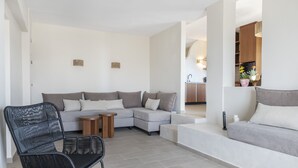 A modern living room with a sectional sofa, a black wicker chair, and a small wooden table. - Casa di Demezzo (Sitia)