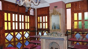 A room with wooden lattice windows, a fireplace, and a mirror with ornate gold detailing. - Villa DALIA (Ghmate)