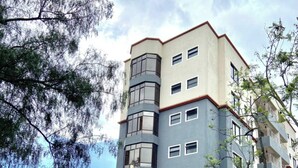 A multi-story residential building with a modern design, featuring a mix of balconies and windows, and a gated entrance. - Midtown B61 Apartment (Nakuru)